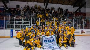 The Warriors pose for a team picture on the ice, with the McCaw Cup and OUA championship banner